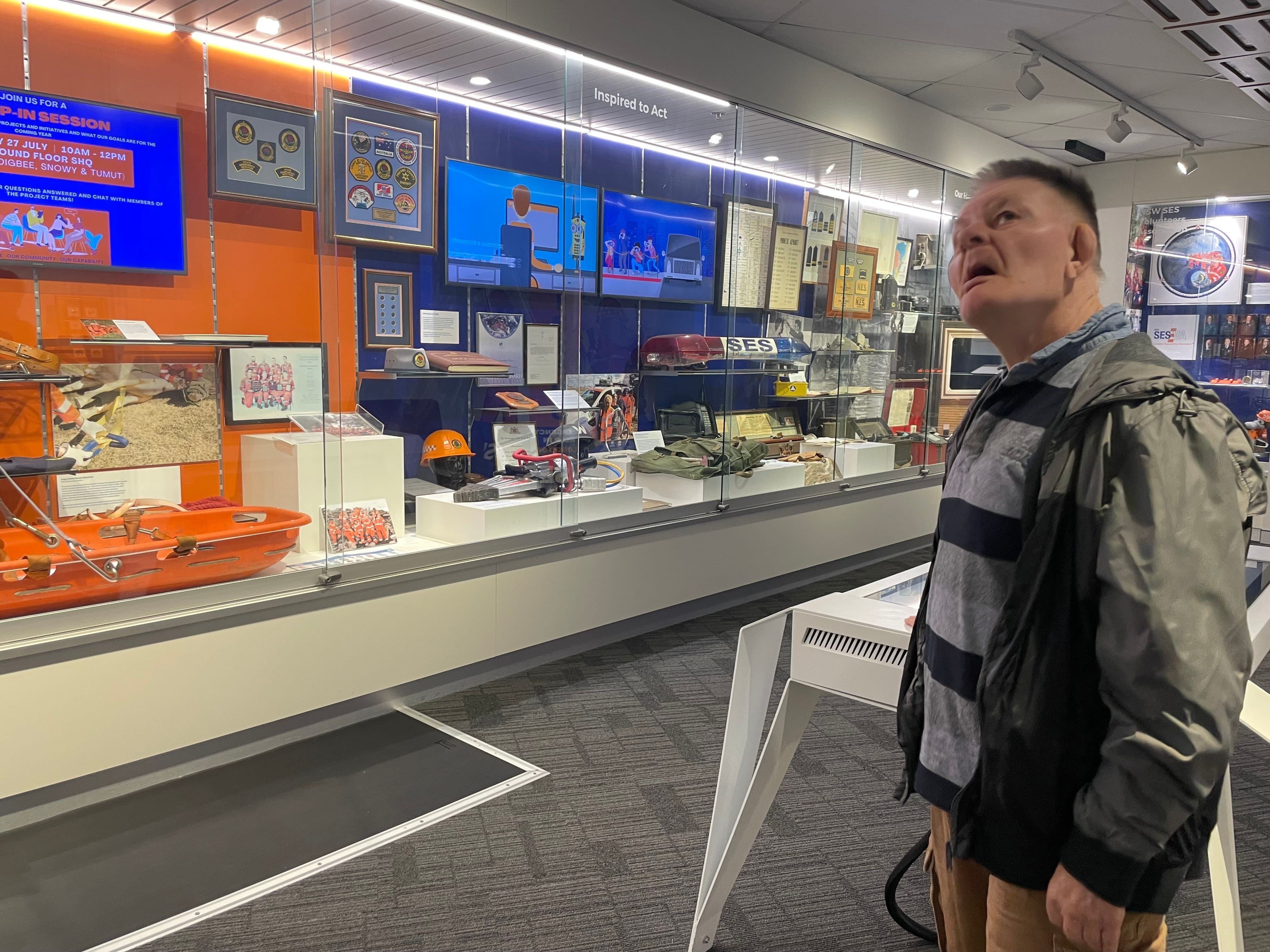 Picture of a gentlemen looking at his food options on a wall mounted menu at a takeaway shop